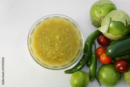 Bowl with delicious salsa sauce and ingredients on white background, flat lay
