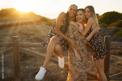Obraz na płótnie Joyful diverse girlfriends embracing on wooden pier