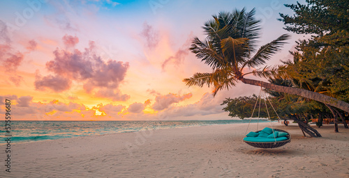 Romantic beach sunset. Palm tree with swing hanging before majestic clouds sky. Dream nature landscape, tropical island paradise, couple destination. Love coast, closeup sea sand. Relax pristine beach © icemanphotos