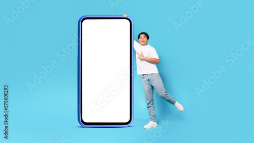 Japanese Male Teen Posing Near Big Cellphone Screen In Studio
