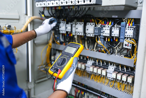 Electricity or electrical maintenance service, Electrician hand holding measuring meter checking electric current voltage circuit breaker cable wiring check main power load center distribution board.