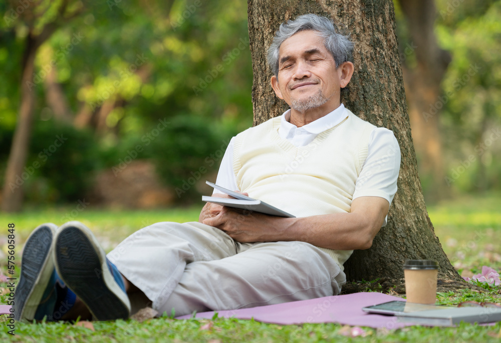 an old man sitting against a tree his eyes closed and relax while reading a book in the park,concept for elderly people activity,hobbies,relaxing,resting,wellbeing an old man sitting against a tree his eyes closed and relax while reading a book in the park,concept for elderly people activity,hobbies,relaxing,resting,wellbeing