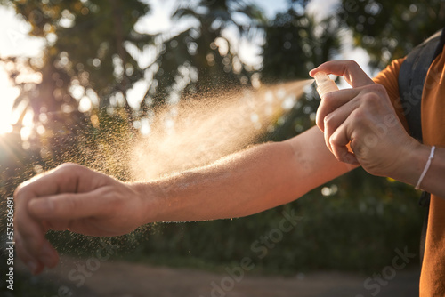 Man is applying insect repellent on his hand against palm trees. Prevention against mosquito bite in tropical destination. ..