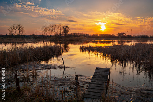 A small wooden pier on the lake shore with sunset