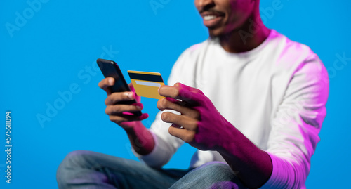 Unrecognizable black guy holding smartphone and credit card, cropped © Prostock-studio