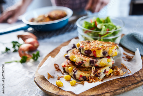Delicious corn fritters with salad on wooden board