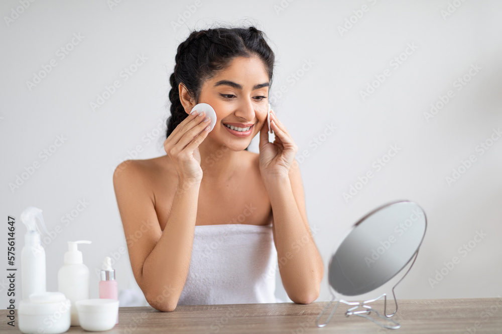 Portrait Of Beautiful Indian Woman Cleansing Skin With Cotton Pad Near Mirror Portrait Of Beautiful Indian Woman Cleansing Skin With Cotton Pad Near Mirror