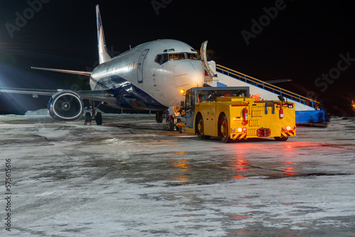 Close-up with high detail of a large wide-body passenger aircraft standing in the airport parking lot during ground handling at night
