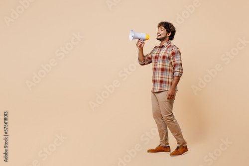Full body young Indian man wears brown shirt casual clothes hold in hand megaphone scream announces discounts sale Hurry up isolated on plain pastel light beige background. People lifestyle concept. © ViDi Studio