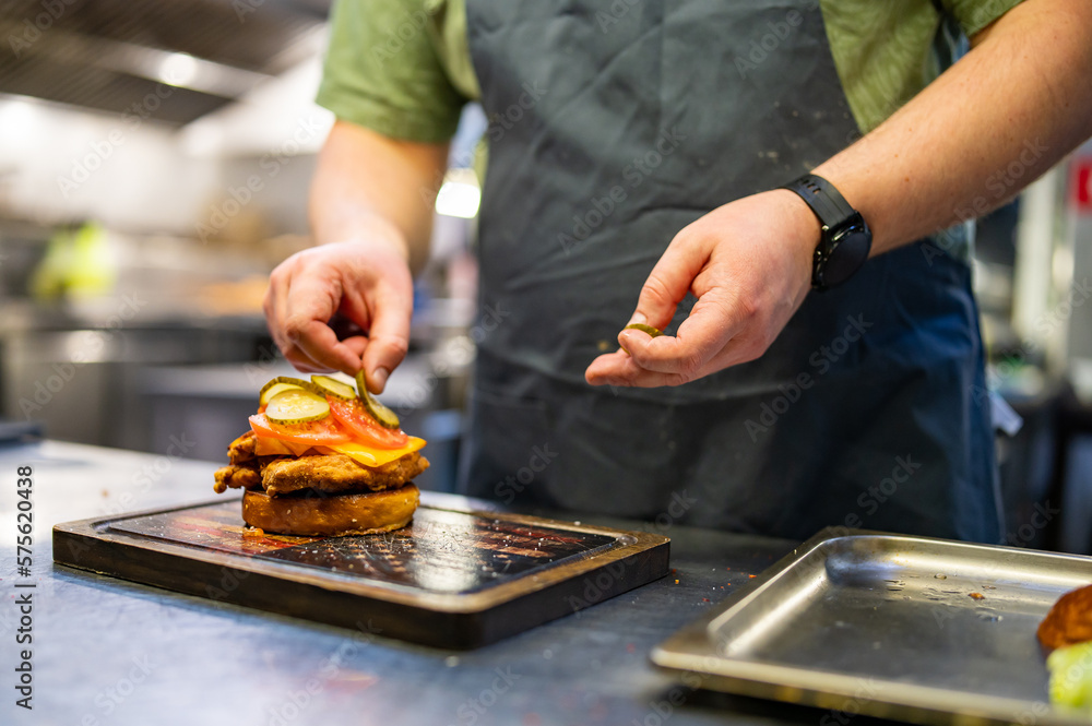 chef hand cooking chickenburger on restaurant kitchen