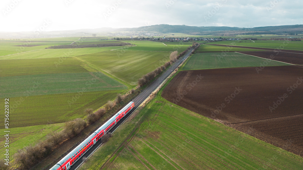 aerial view of train driving through the fields in the countryside