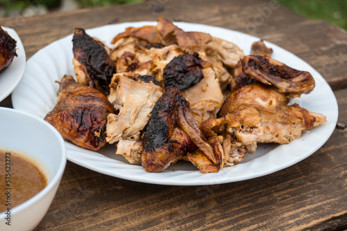 A plate of chopped Lechon Manok, or roasted chicken served outside at a bench with gravy. photo