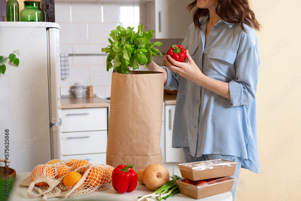 Woman at home getting groceries out of a shopping bag with grocery
