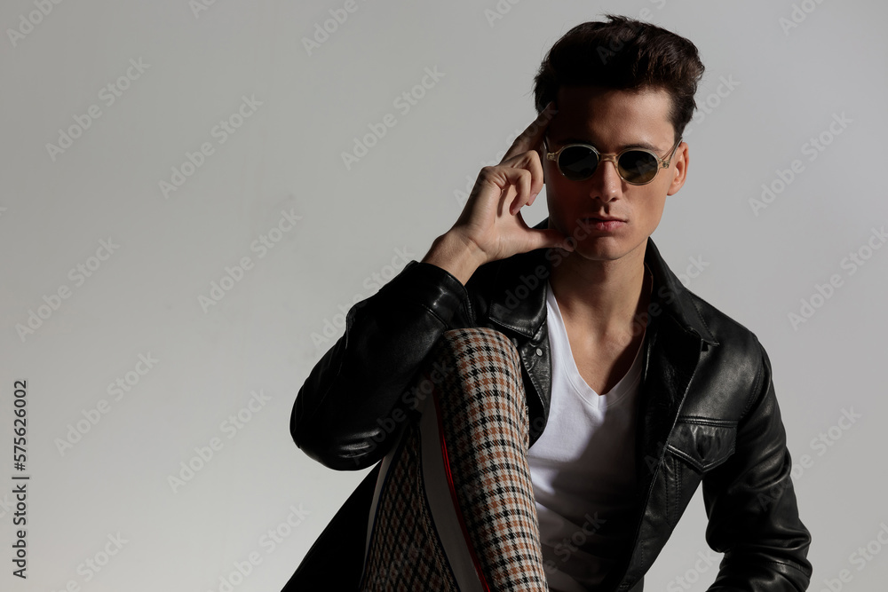 thoughtful cool guy with leather jacket holding fingers to temple and thinking thoughtful cool guy with leather jacket holding fingers to temple and thinking