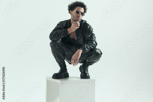 casual man squatting on the chair and touching his chin