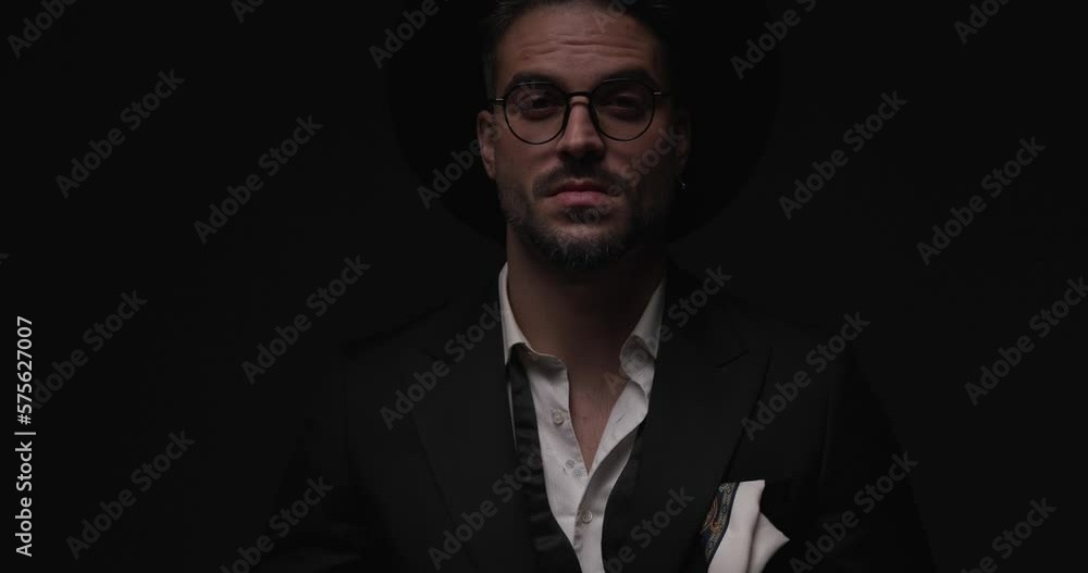confident elegant man looking down, adjusting bracelets, smiling and flirting while adjusting glasses and looking to side while camera is zooming in in flash lights confident elegant man looking down, adjusting bracelets, smiling and flirting while adjusting glasses and looking to side while camera is zooming in in flash lights