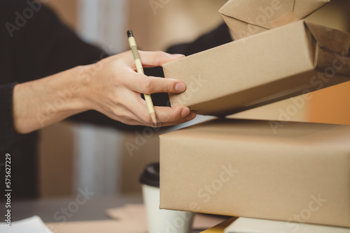 Starting small of online SME businesses owners man entrepreneurs working, box and check online orders to prepare to pack the boxes, sell to customers on e-business cyberspace from home