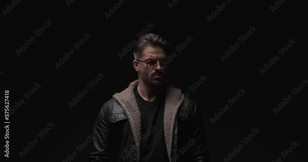 proud cool guy with leather jacket and wool cardigan holding hand in pocket, looking to side and fixing outfit while posing with flash lights on proud cool guy with leather jacket and wool cardigan holding hand in pocket, looking to side and fixing outfit while posing with flash lights on