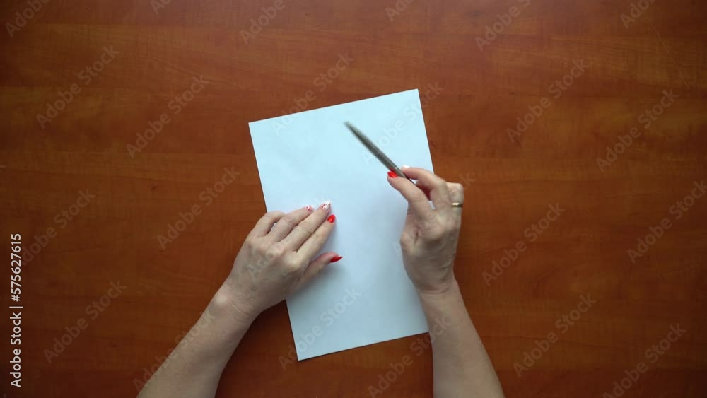 Close-up of female hands nervously twisting the handle over a white sheet. The girl is considering a solution to the problem. Close-up of female hands nervously twisting the handle over a white sheet. The girl is considering a solution to the problem.