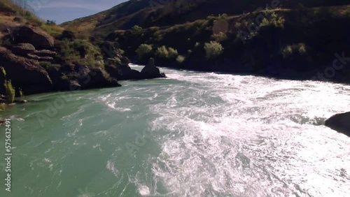 Flying low above water rapids of beautiful river gorge. Kawarau Gorge in New Zealand. photo