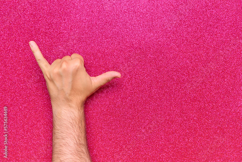 gesture with man's left hand of relaxation shaka or drink in man's hand on glow pink background