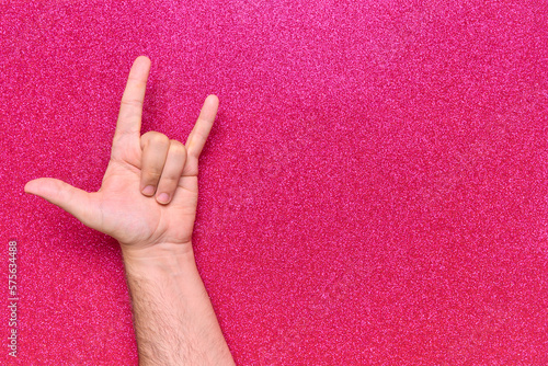 hand gesture horns rock and roll skateboarding bottom with 3 fingers on pink background with glitter photo