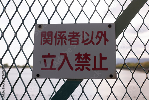 A close-up photo of a "No Trespassing" sign posted on a fence to indicate that entry is prohibited to unauthorized individuals.