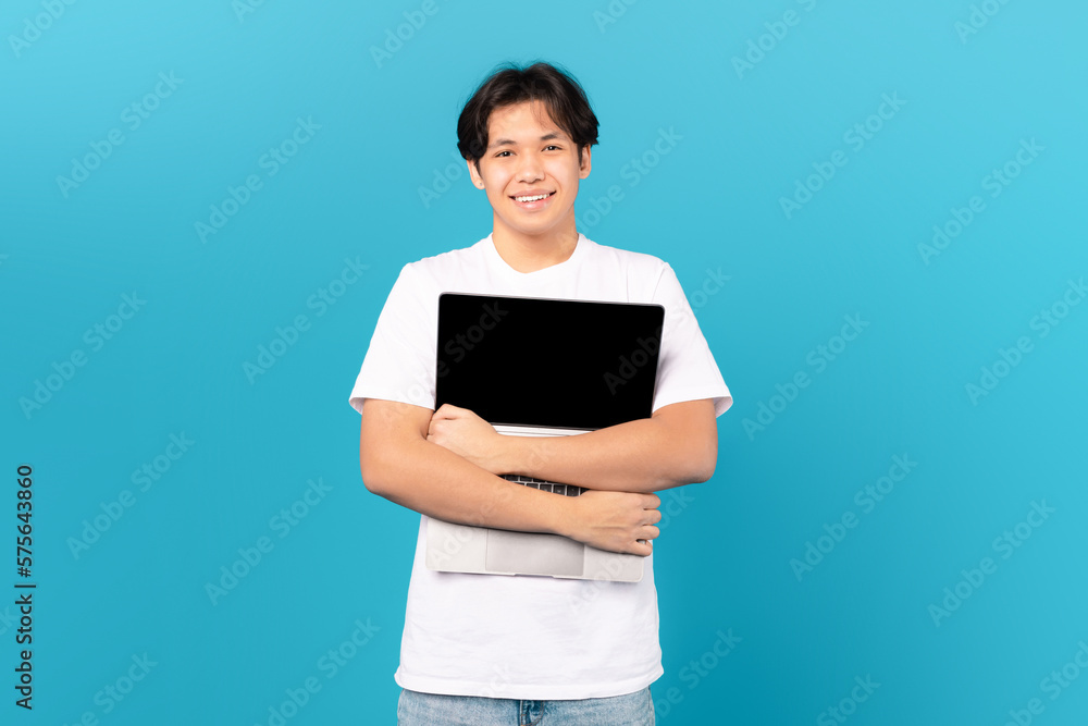 Asian Teen Guy Holding Hugging Laptop Standing Over Blue Background Asian Teen Guy Holding Hugging Laptop Standing Over Blue Background