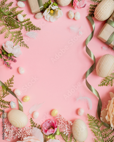 Canvas Print beautiful easter frame composition with wooden easter eggs, flowers, ribbons and gifts on a pastel pink background