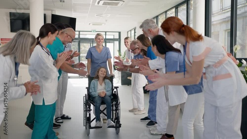 Medical staff clapping to little girl patient who recovered from serious illness.