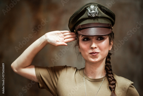 American pilot. A beautiful young woman in a uniform and with a weapon on the background of a metal wall. Staged photo. Studio light.