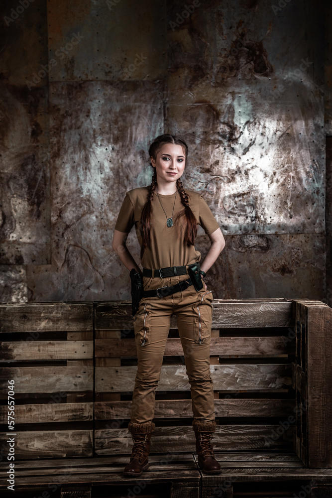 American pilot. A beautiful young woman in a uniform and with a weapon on the background of a metal wall. Staged photo. Studio light. American pilot. A beautiful young woman in a uniform and with a weapon on the background of a metal wall. Staged photo. Studio light.
