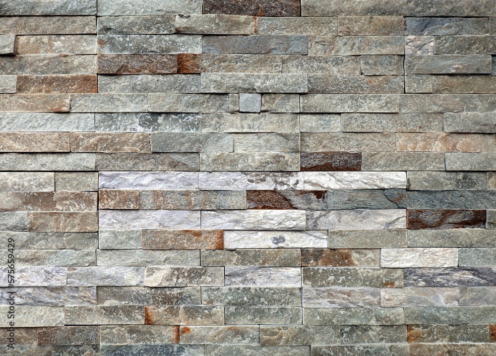 Stone wall paneling made of stacked stripes rock bricks. The colors are white, brown, and gray. Texture. Stone wall paneling made of stacked stripes rock bricks. The colors are white, brown, and gray. Texture.