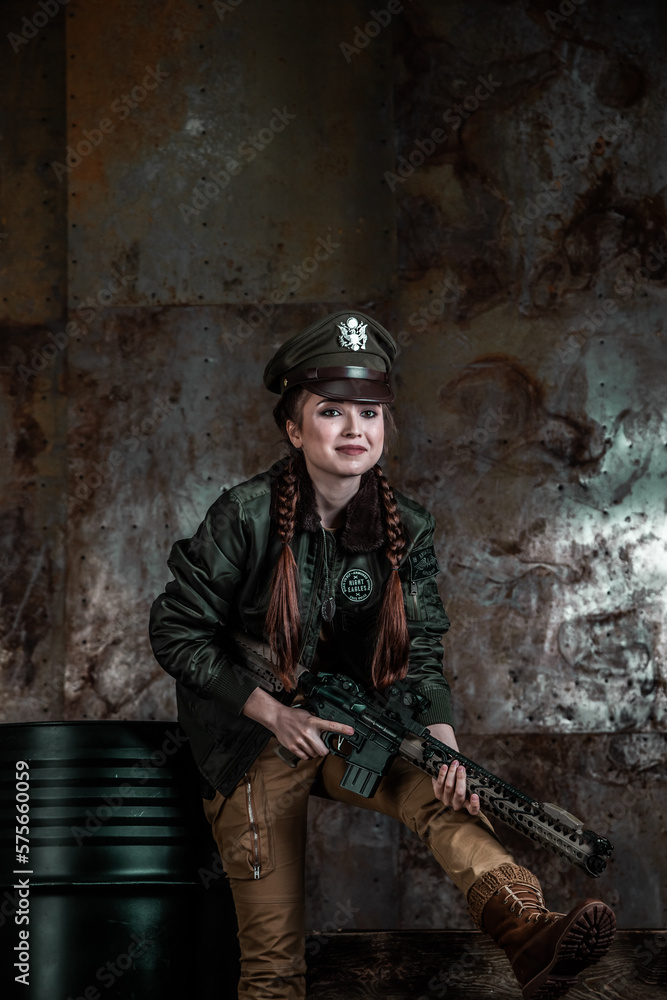 American pilot. A beautiful young woman in a uniform and with a weapon on the background of a metal wall. Staged photo. Studio light. American pilot. A beautiful young woman in a uniform and with a weapon on the background of a metal wall. Staged photo. Studio light.