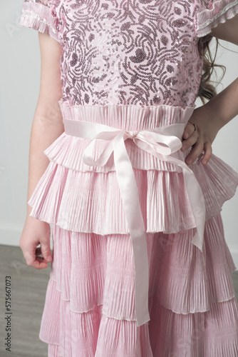 details of an embroidered pink dress with sequins and pleated belt zone. Girgl wearing shyny party dress. unrecognizable person. photo