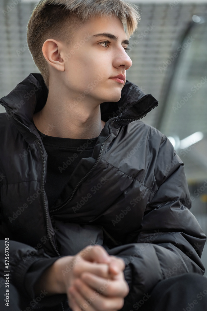 Portrait of a teenager sitting on an escalator climbs the stairs. vertical Portrait of a teenager sitting on an escalator climbs the stairs. vertical