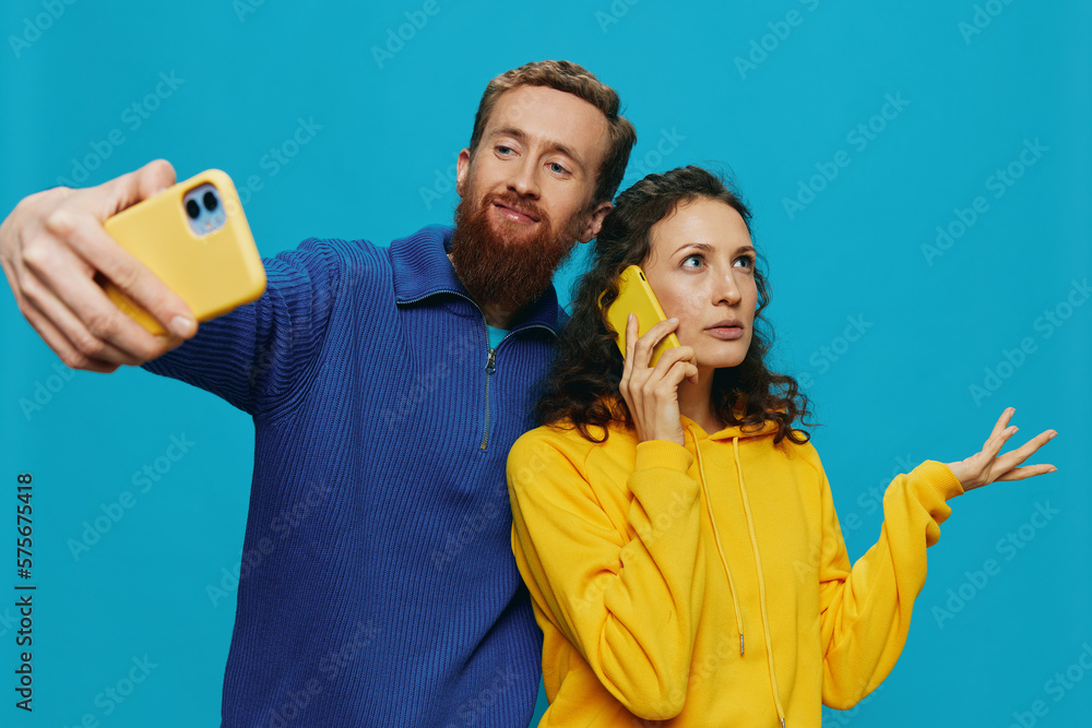 Woman and man funny couple with phones in hand taking selfies crooked smile fun, on blue background. The concept of real family relationships, talking on the phone, work online. Woman and man funny couple with phones in hand taking selfies crooked smile fun, on blue background. The concept of real family relationships, talking on the phone, work online.