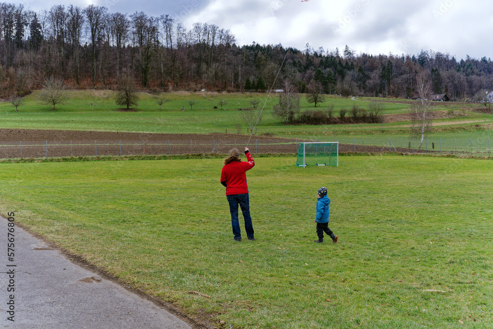 Mother with child are playing with kite at City of Zürich district Schwamendingen on a cloudy winter day. Photo taken February 26th, 2023, Zurich, Switzerland. Mother with child are playing with kite at City of Zürich district Schwamendingen on a cloudy winter day. Photo taken February 26th, 2023, Zurich, Switzerland.