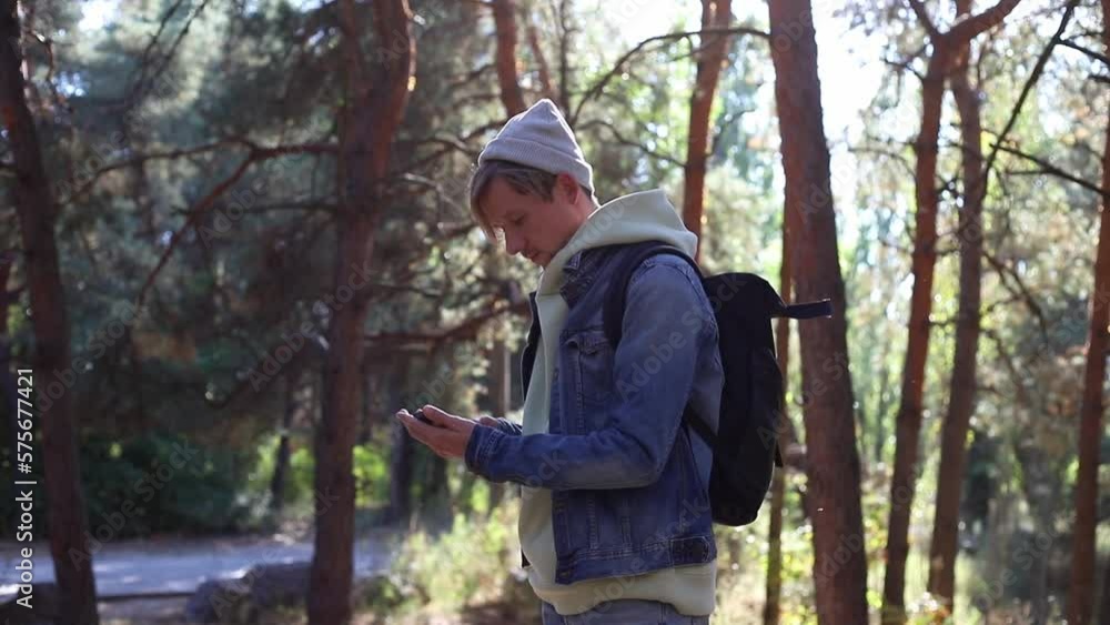 Portrait of a mobile phone in the hands of a male traveler walking through the forest. Social networks Navigator and messenger. Use your mobile phone for a walk in the woods Portrait of a mobile phone in the hands of a male traveler walking through the forest. Social networks Navigator and messenger. Use your mobile phone for a walk in the woods
