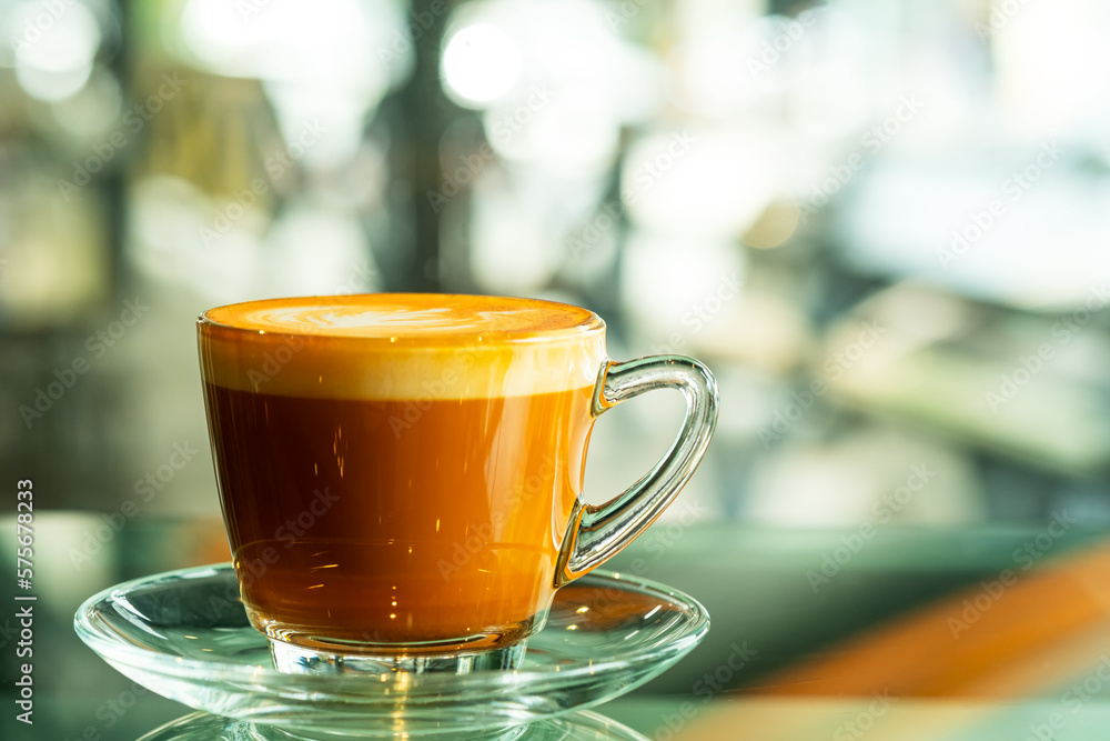 Cappuccino or latte with leaves pattern foam, coffee cleared cup closeup. Cafe and bar with bokeh background Cappuccino or latte with leaves pattern foam, coffee cleared cup closeup. Cafe and bar with bokeh background