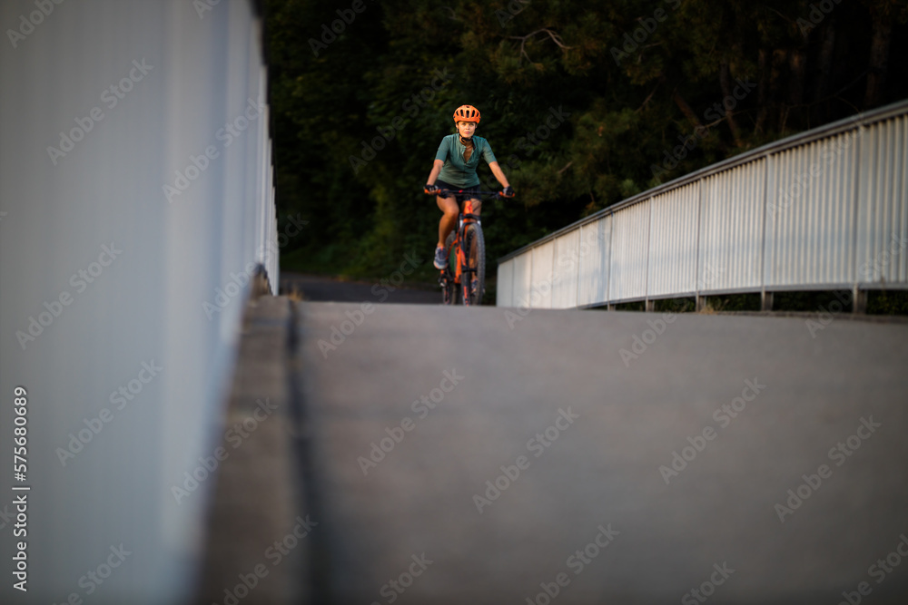 Pretty, young woman with her mountain bike going for a ride past the city limits, getting the daily cardio dose