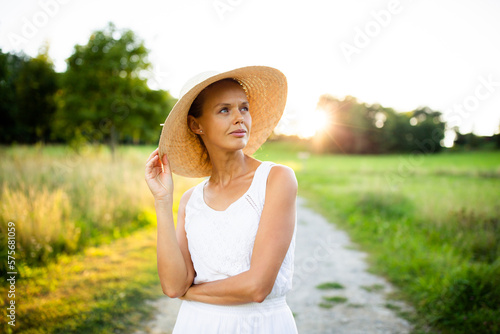 Pretty, young elegant woman with a hat in warm evening sunlight