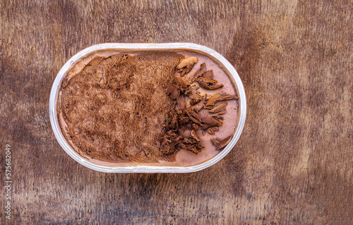 Chocolate icecream on a wooden rustic background. Dark chocolate ice cream in a conteiner.