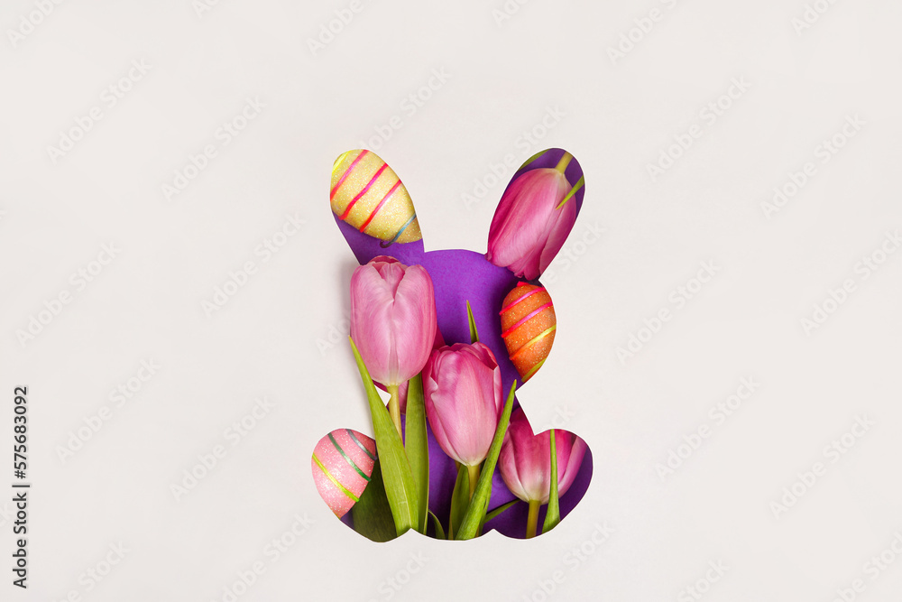 Bunny shape Easter holiday composition with pink tulips and colorful eggs, white paper background. Easter greeting card