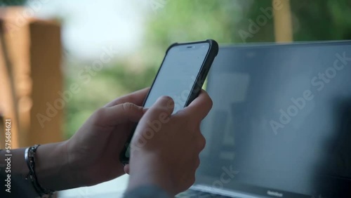 The camera is focused on the hands of a woman who pokes at a mobile phone