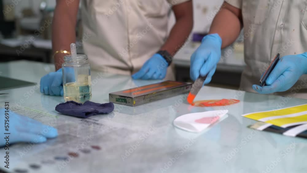 Factory workers doing sample test for orange paint Factory workers doing sample test for orange paint