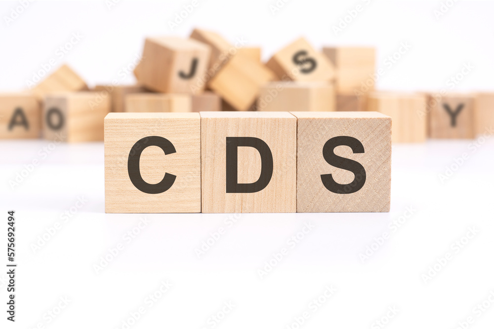 text CDS - Credit Default Swap - is written on three wooden cubes standing on a white table. in the background - a mountain of wooden cubes with letters. text CDS - Credit Default Swap - is written on three wooden cubes standing on a white table. in the background - a mountain of wooden cubes with letters.