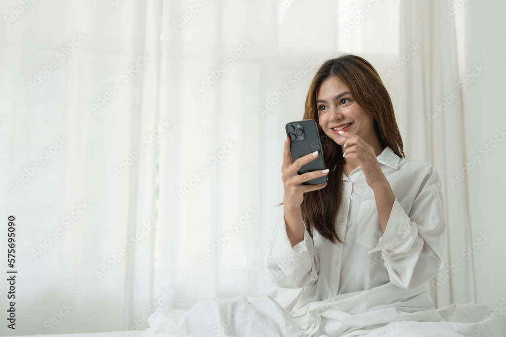 Beautiful young asian woman smiling sitting relax on the bed in the morning, girl using mobile smart phone talking enjoy, communication and social network concept. Beautiful young asian woman smiling sitting relax on the bed in the morning, girl using mobile smart phone talking enjoy, communication and social network concept.