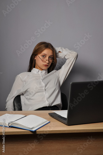 Portrait of an angry business woman sitting near the table and looking at the camera. Grumpiness and work concept