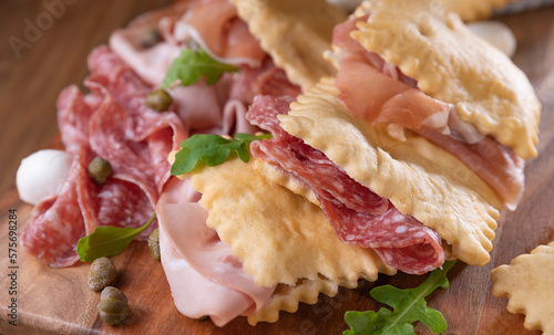 Crescentina. Food of Emilia Romagna region, deep fried bread gnocco fritto or crescentina. Starter or aperitif in Italy. Creshantina with prosciutto crudo, mortadella, Milanese salami, capers, cheese 